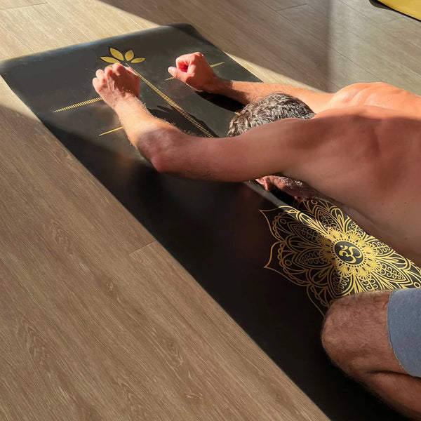 esterilla de yoga de viaje antideslizante premium diseño energia negro con tinta dorada en uso durante una práctica