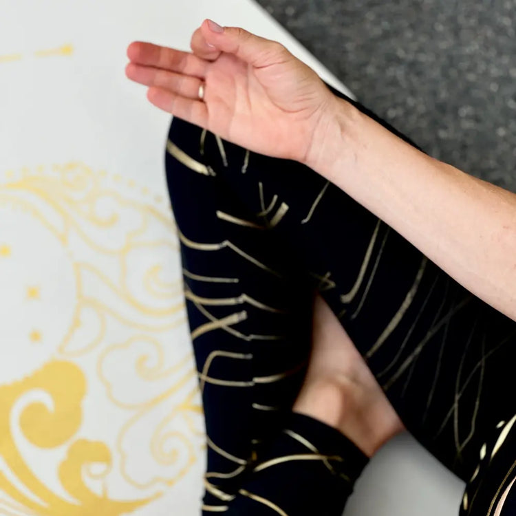 esterilla de yoga antideslizante premium diseño energia blanco con tinta dorada en uso durante una práctica